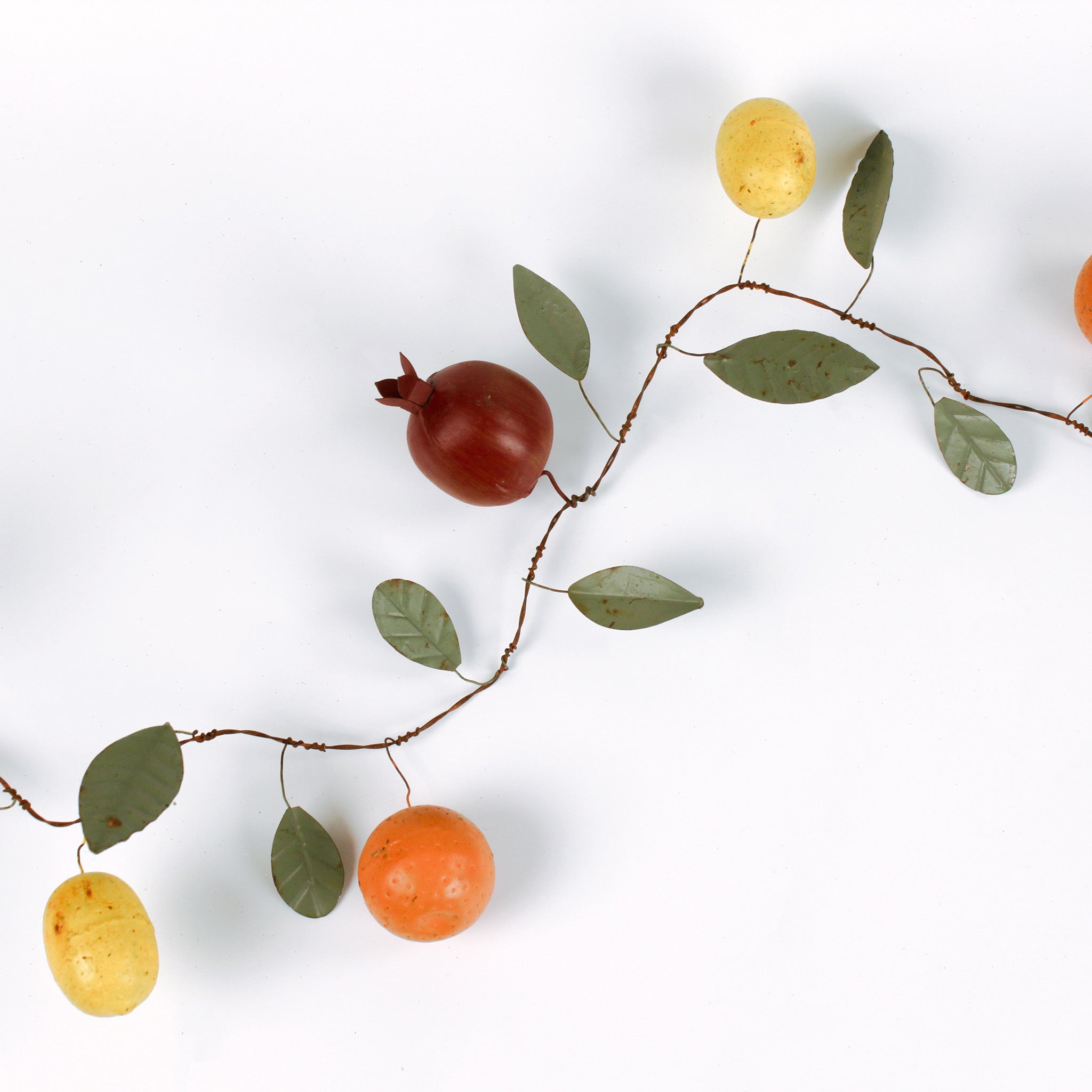 Handcrafted tole metal garland featuring lifelike fruit accents including pomegranate, orange, and lemon with green leaves