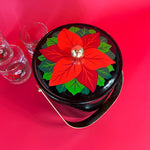 top view of a vintage Christmas ice bucket with poinsettia motif lid and three matching glasses
