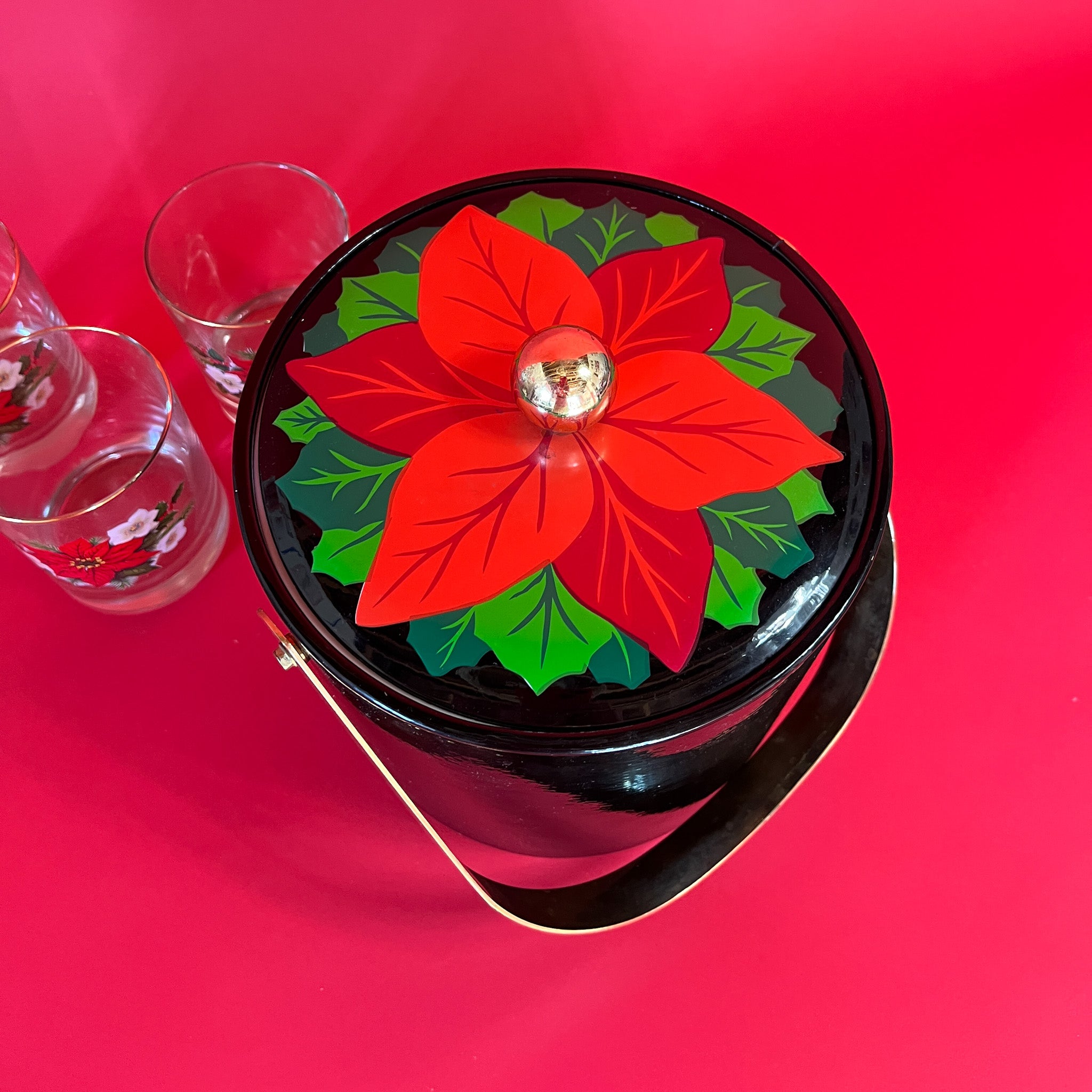top view of a vintage Christmas ice bucket with poinsettia motif lid and three matching glasses
