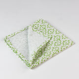 Close-up of folded cloth napkin showing light green fabric with a small floral pattern.