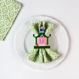 Green patterned cloth napkin styled on a white plate with a decorative pagoda napkin ring.