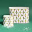 Two sizes of round, decorative caddies with a Christmas tree and gift pattern design, one large and one small, against a green background.