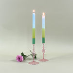 two pink glass candle holder with green tops and candles