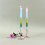two pink glass candle holder with green tops and candles