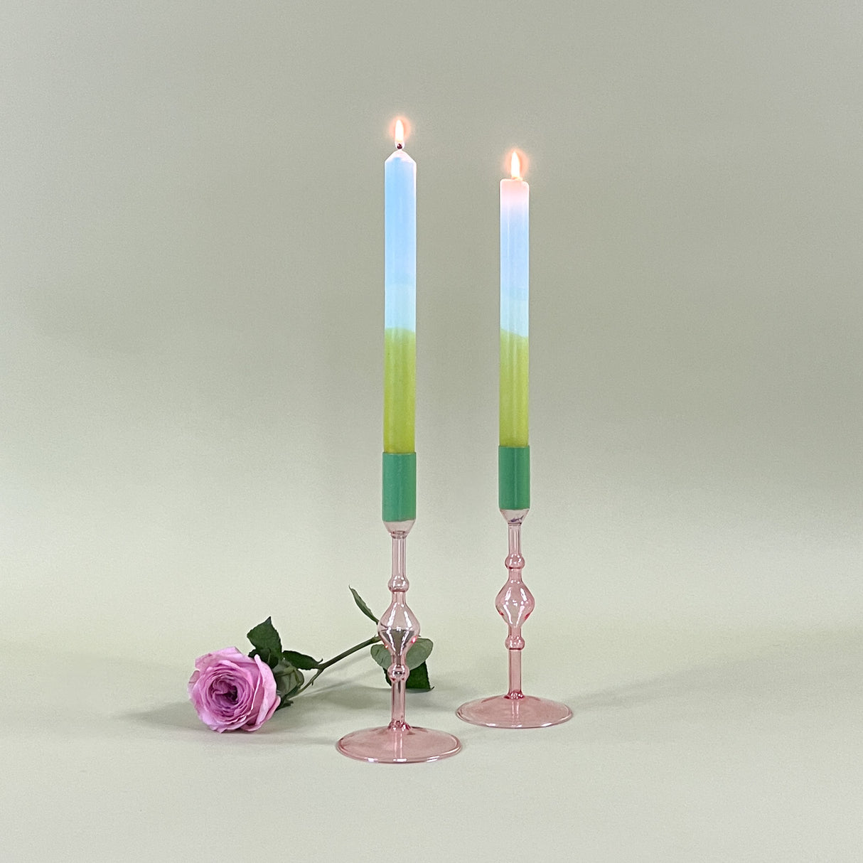 two pink glass candle holder with green tops and candles