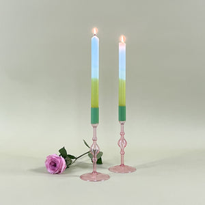 two pink glass candle holder with green tops and candles