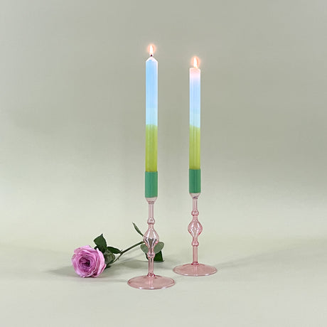 two pink glass candle holder with green tops and candles