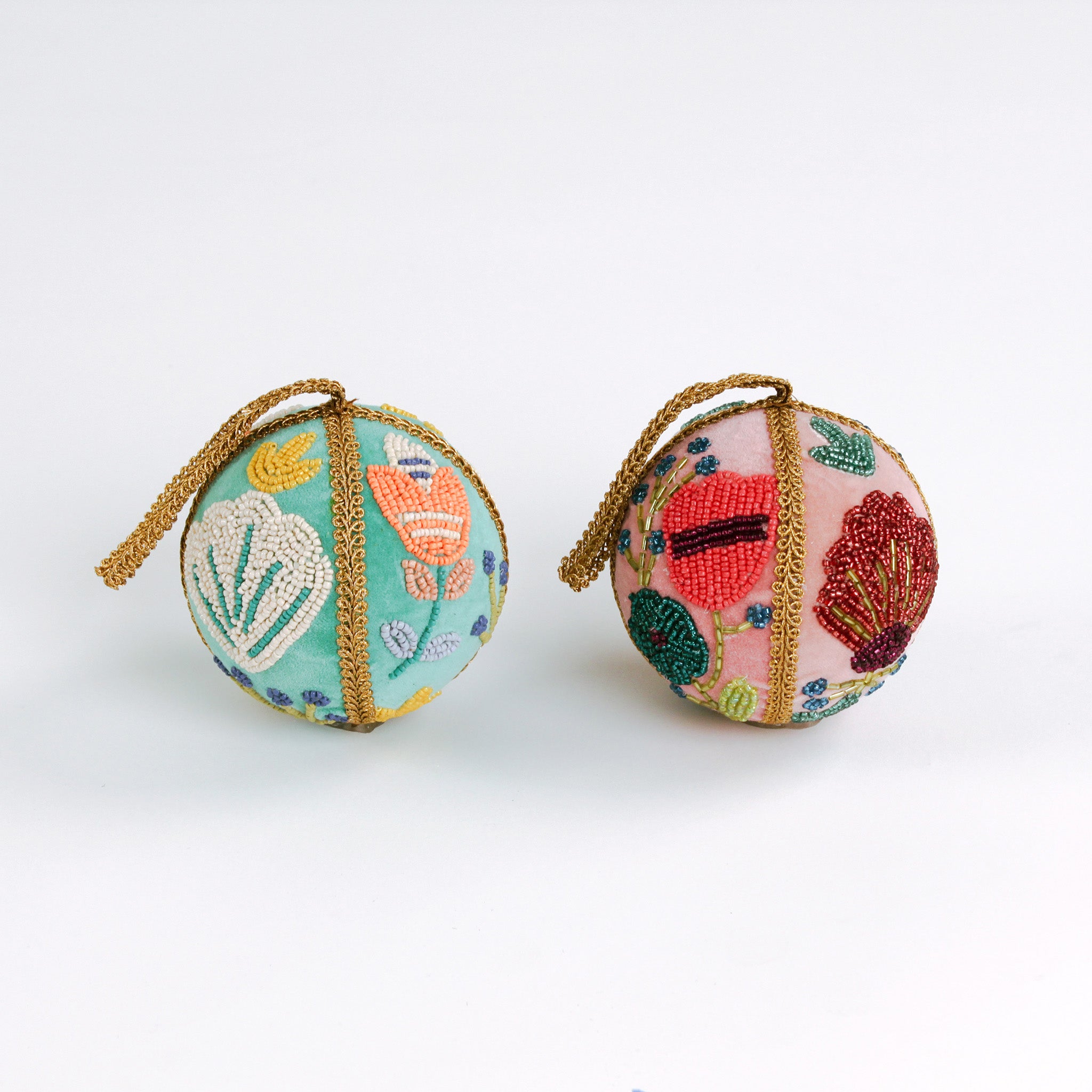 Set of two velvet Christmas ball ornaments in soft pink and mint green, beautifully hand-embroidered with beaded floral designs and finished with gold braided trim and hanging loops