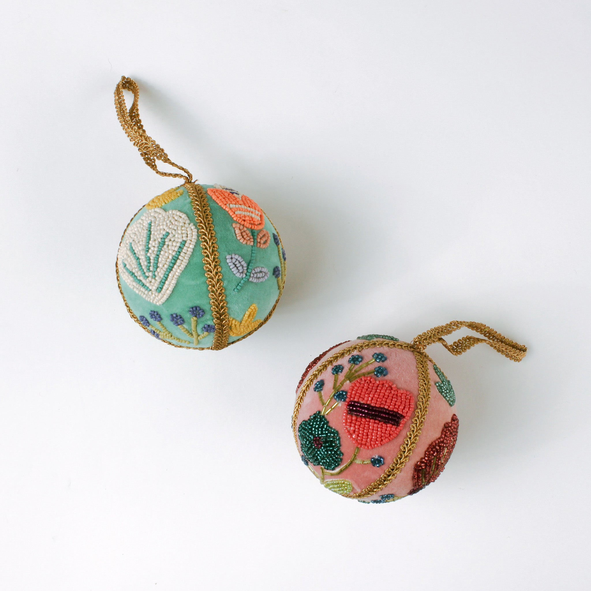 Set of two velvet Christmas ball ornaments in soft pink and mint green, beautifully hand-embroidered with beaded floral designs and finished with gold braided trim and hanging loops