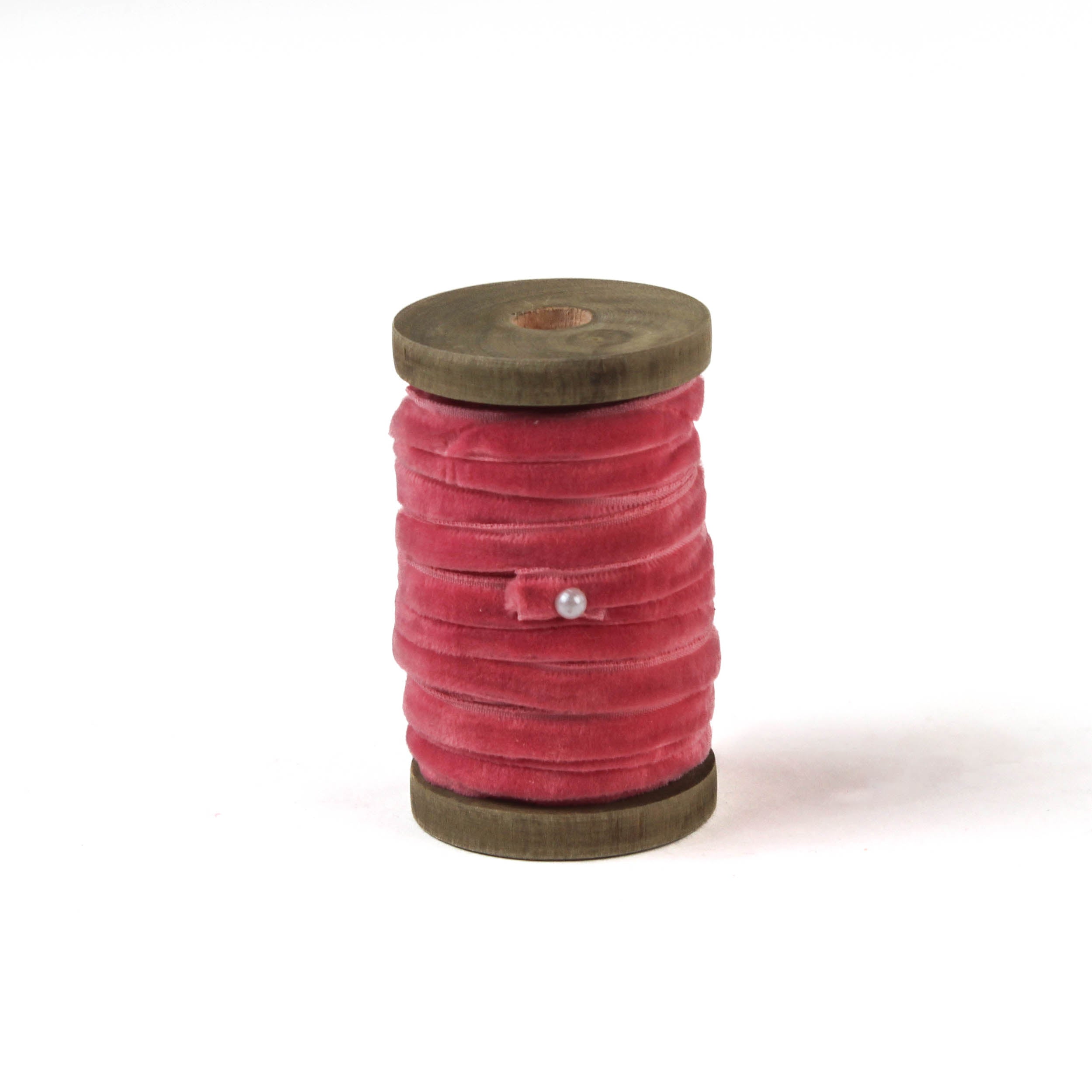 a pink Velvet Ribbon on Wood Spool in a white background