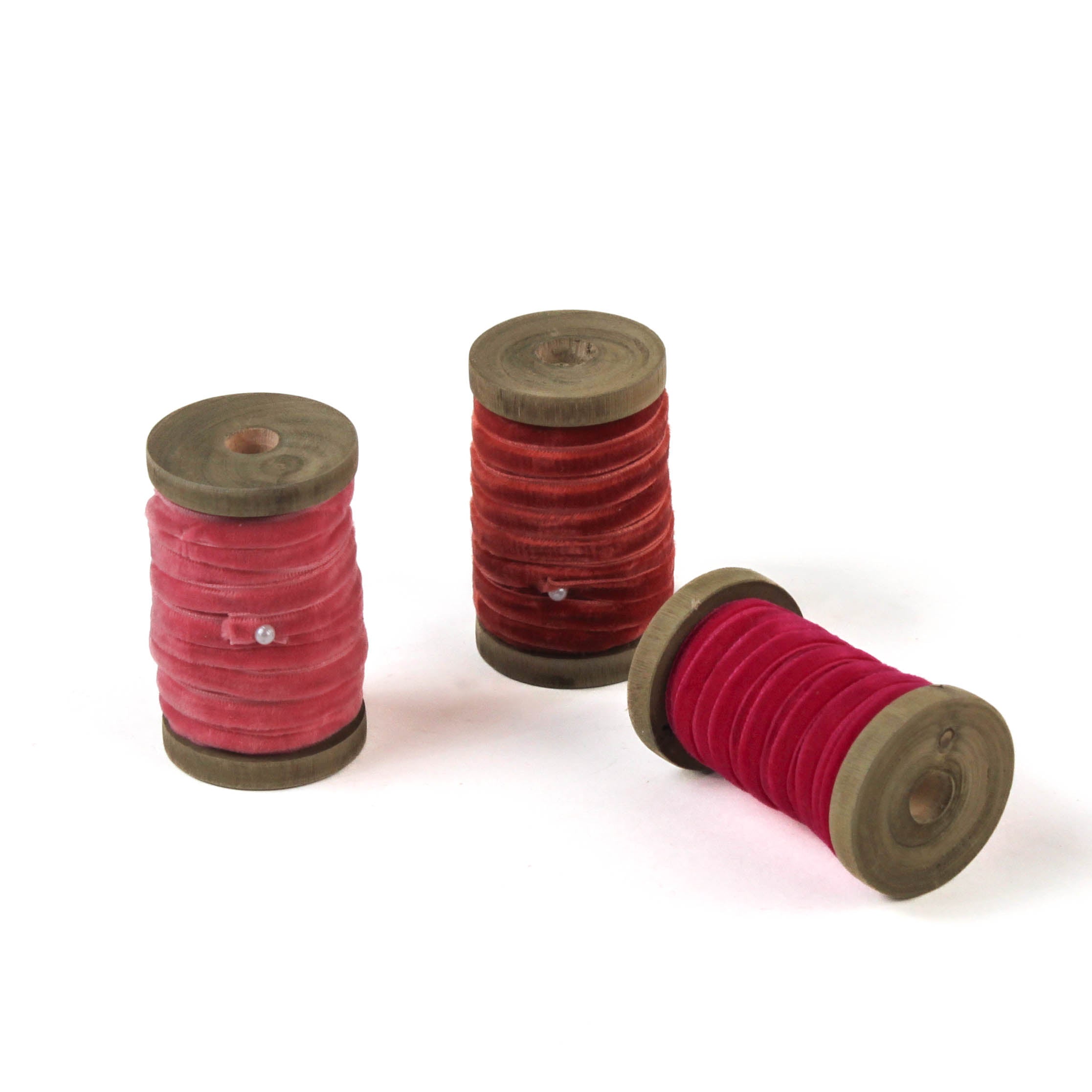 set of 3 Velvet Ribbon on Wood Spool in a white background, 1 being laid down.