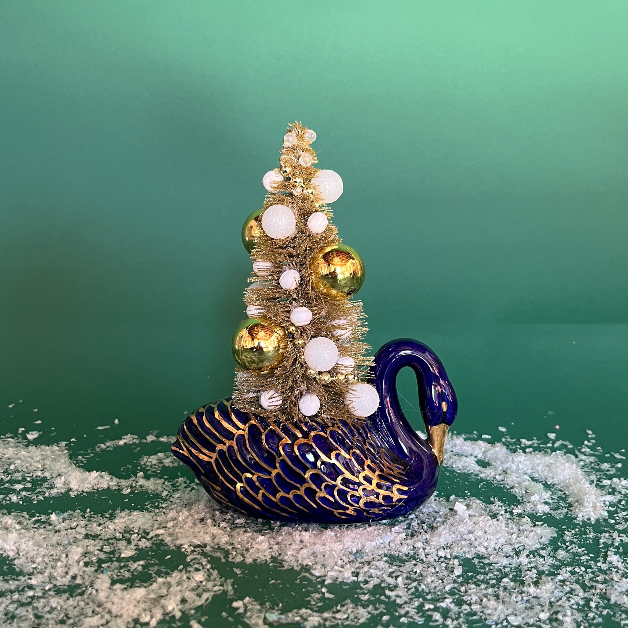 a Vintage Blue/Gold Ceramic Swan w/Gold Christmas Tree Centerpiece against a green background. 