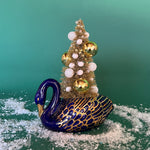 a Vintage Blue/Gold Ceramic Swan w/Gold Christmas Tree Centerpiece against a green background. 