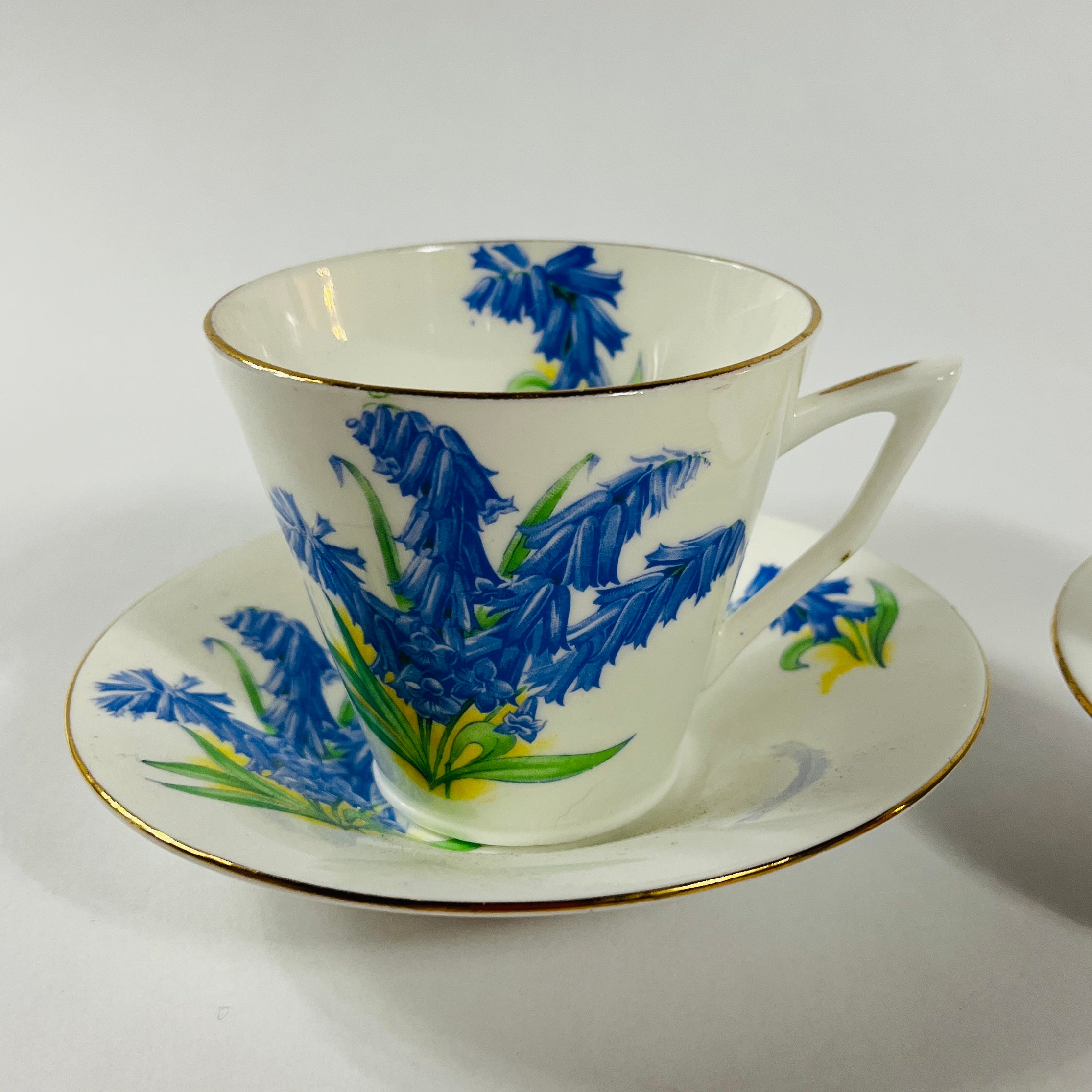 Vintage English bone china cup, saucer, and dessert plate with bluebell floral pattern and gold rim