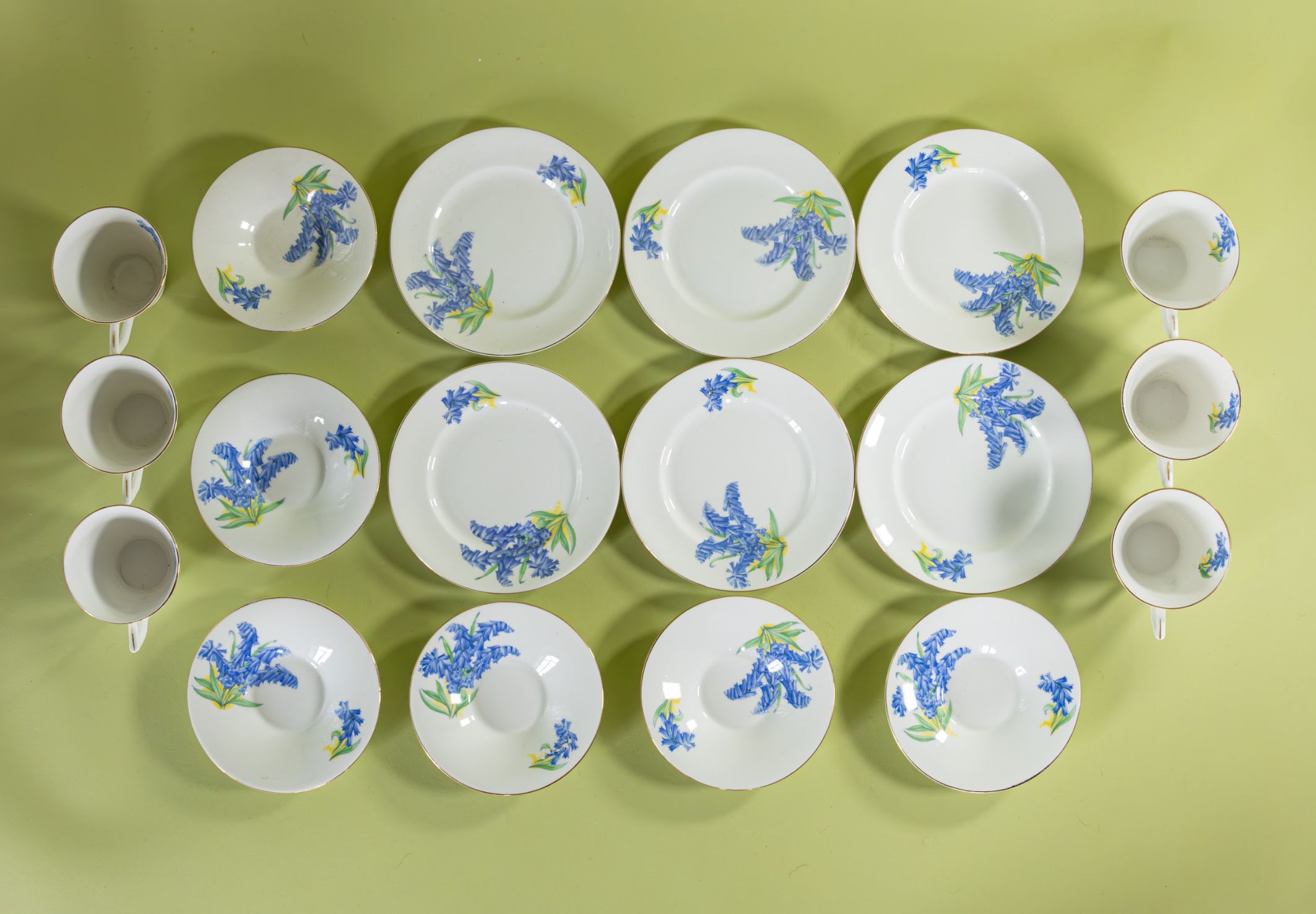 Overhead view of vintage English bone china bluebell dessert set with cups, saucers, and plates arranged together