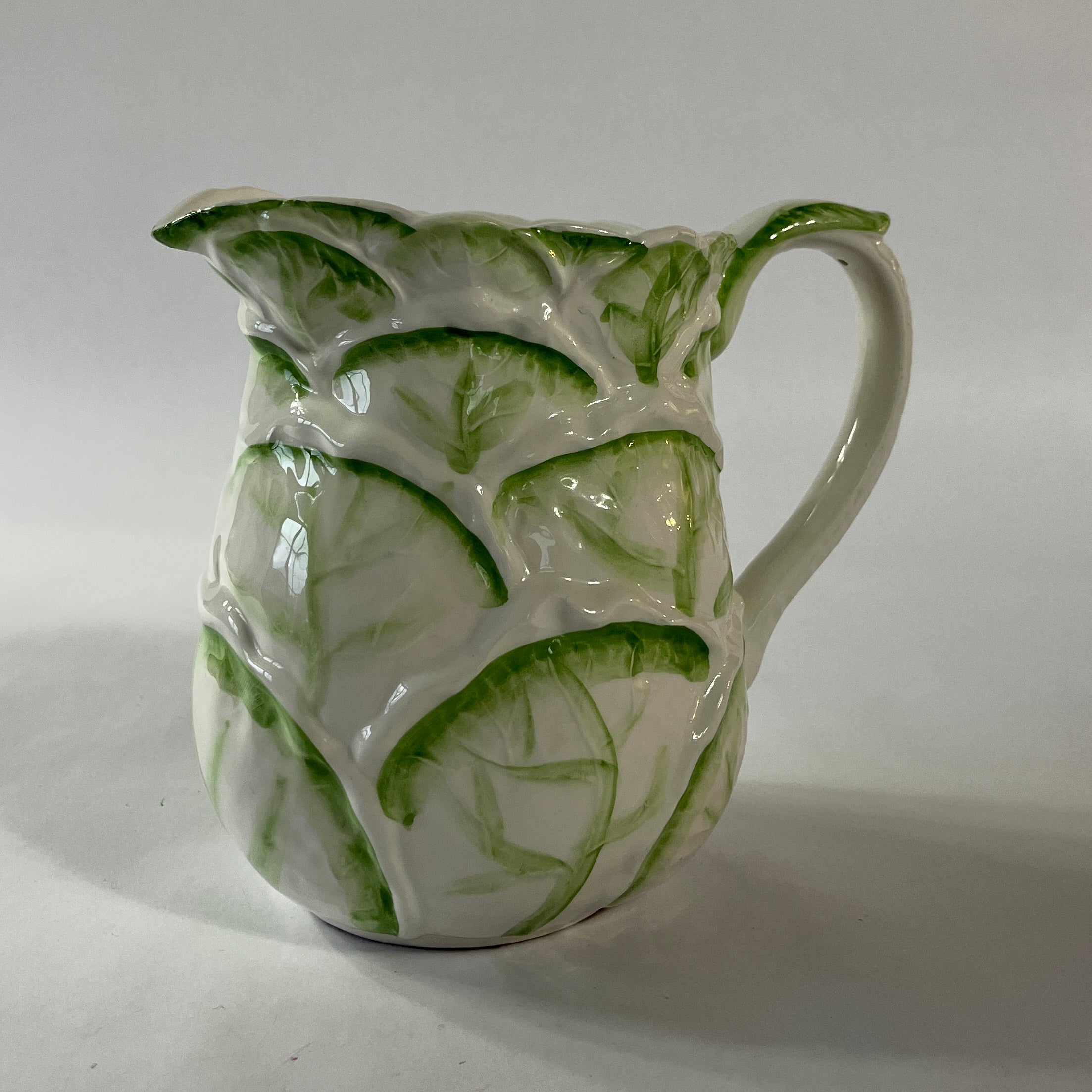 Vintage ceramic pitcher with sculpted leafy design and green hand-painted details