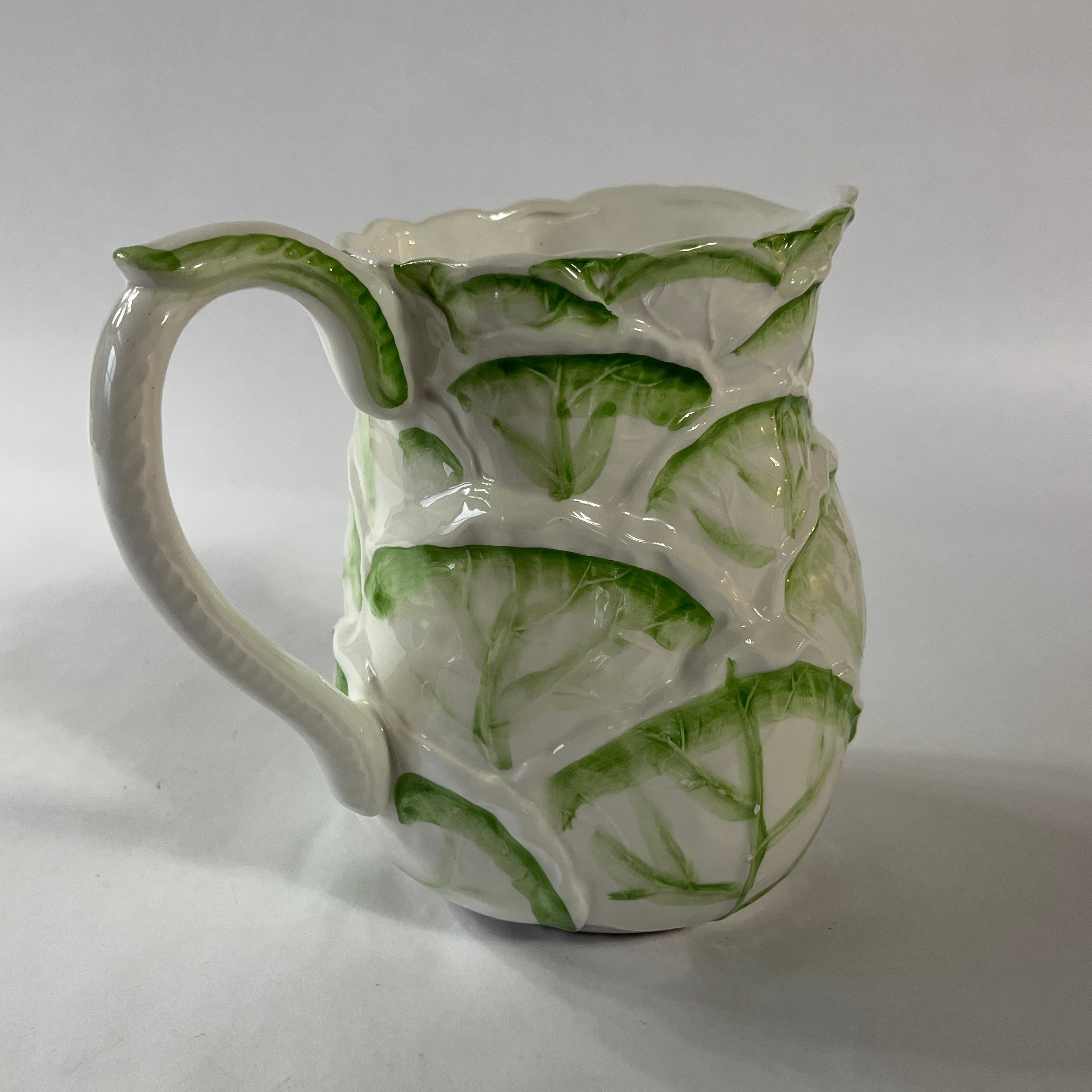 Vintage ceramic pitcher with sculpted leafy design and green hand-painted details