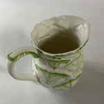 Vintage ceramic pitcher with sculpted leafy design and green hand-painted details
