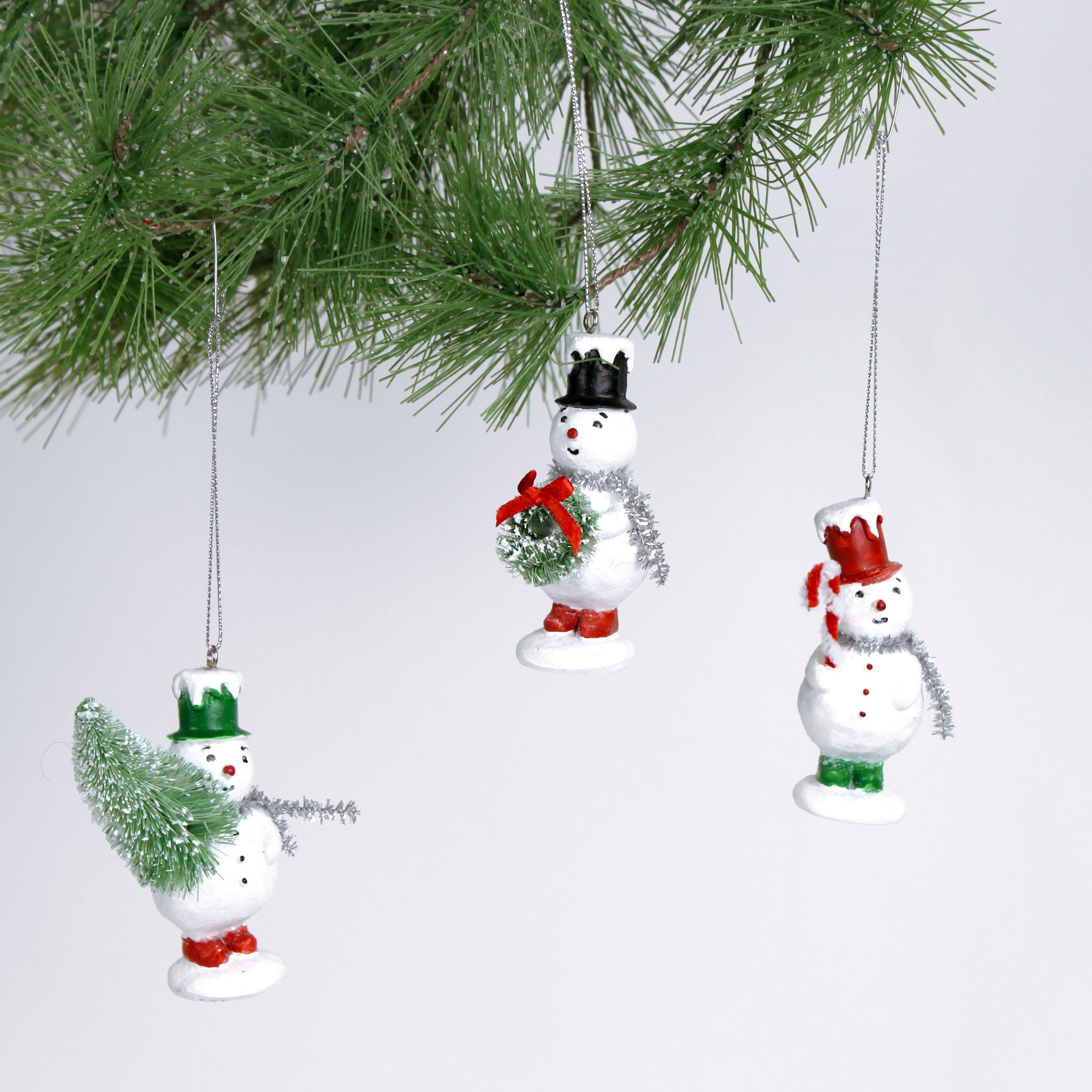 Set of three vintage-style snowman ornaments, each wearing a colorful top hat and scarf
