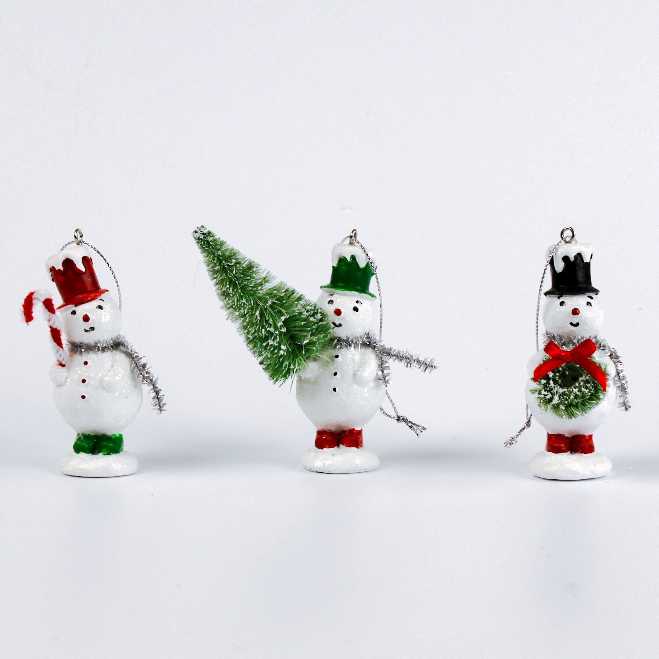 Set of three vintage-style snowman ornaments, each wearing a colorful top hat and scarf