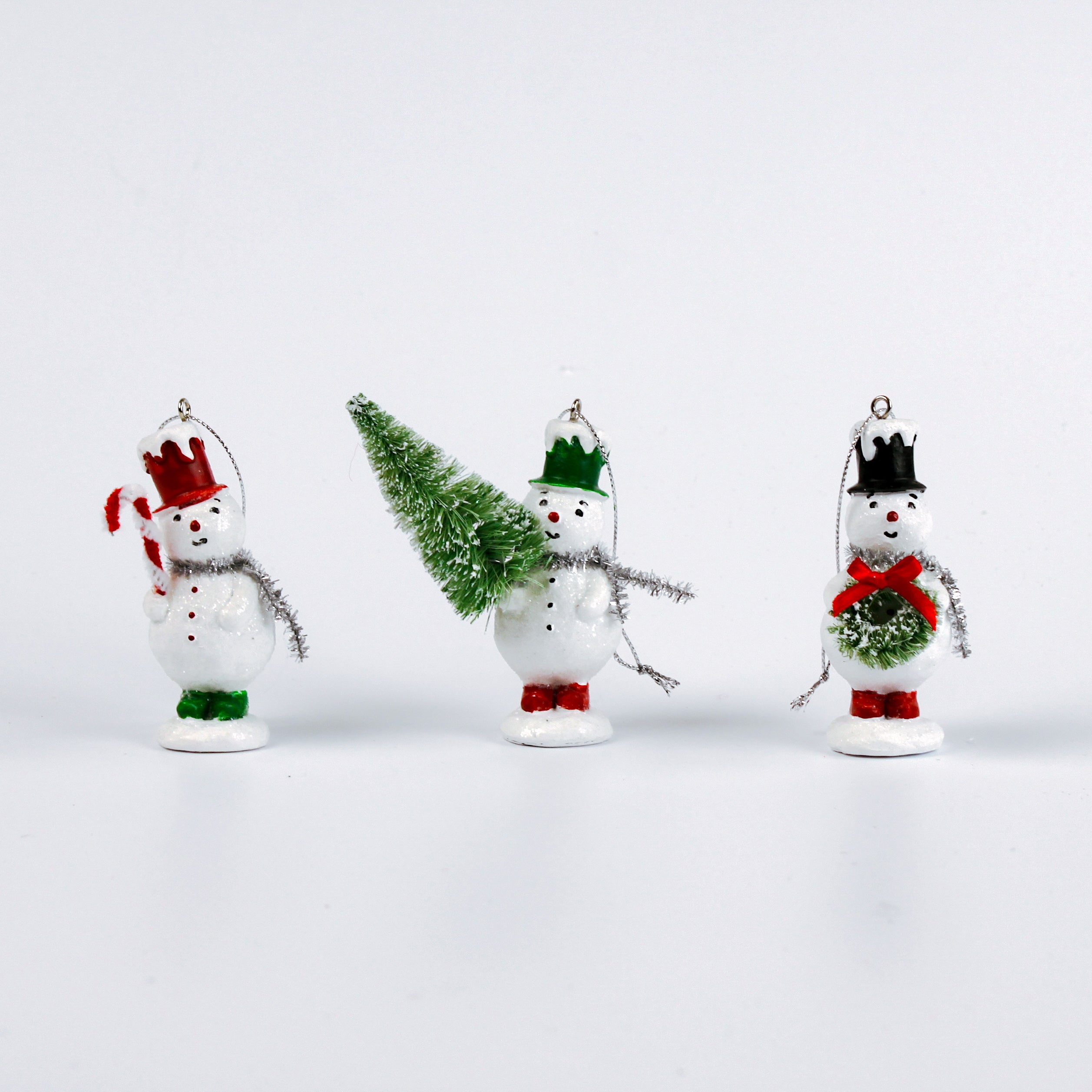 Set of three vintage-style snowman ornaments, each wearing a colorful top hat and scarf