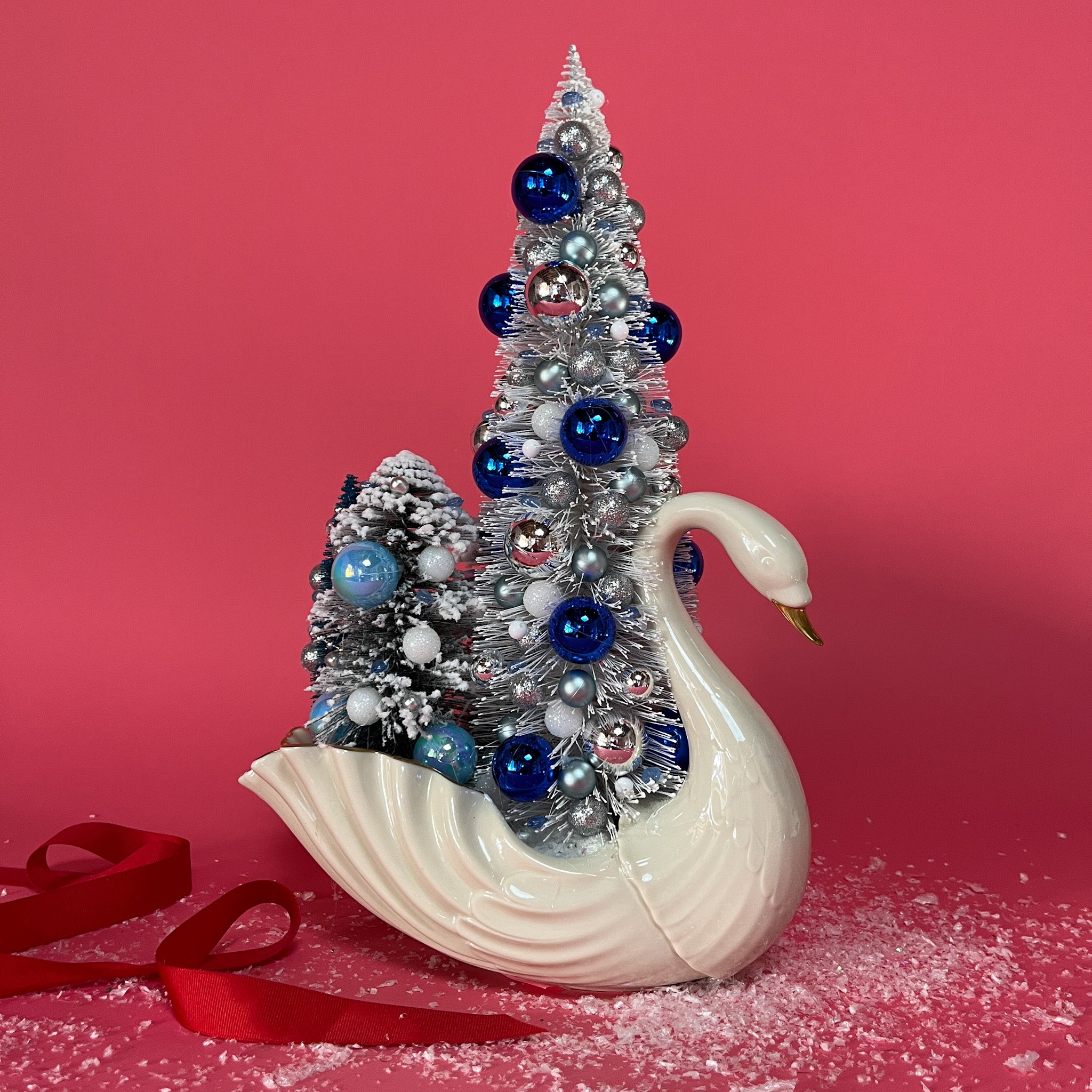 a Vintage White/Gold Ceramic Swan w/ Silver/Blue Glitter Christmas Trees Centerpiece against a red background. 