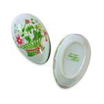a ceramic egg with floral designs split in two on a white background