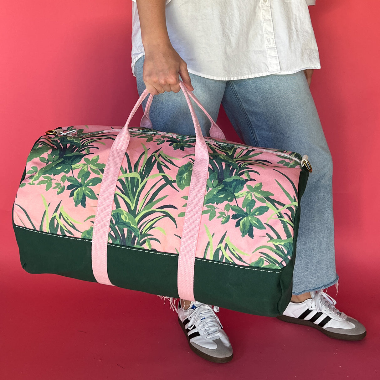 Model walking with the Jungle Road pink and green duffle bag.