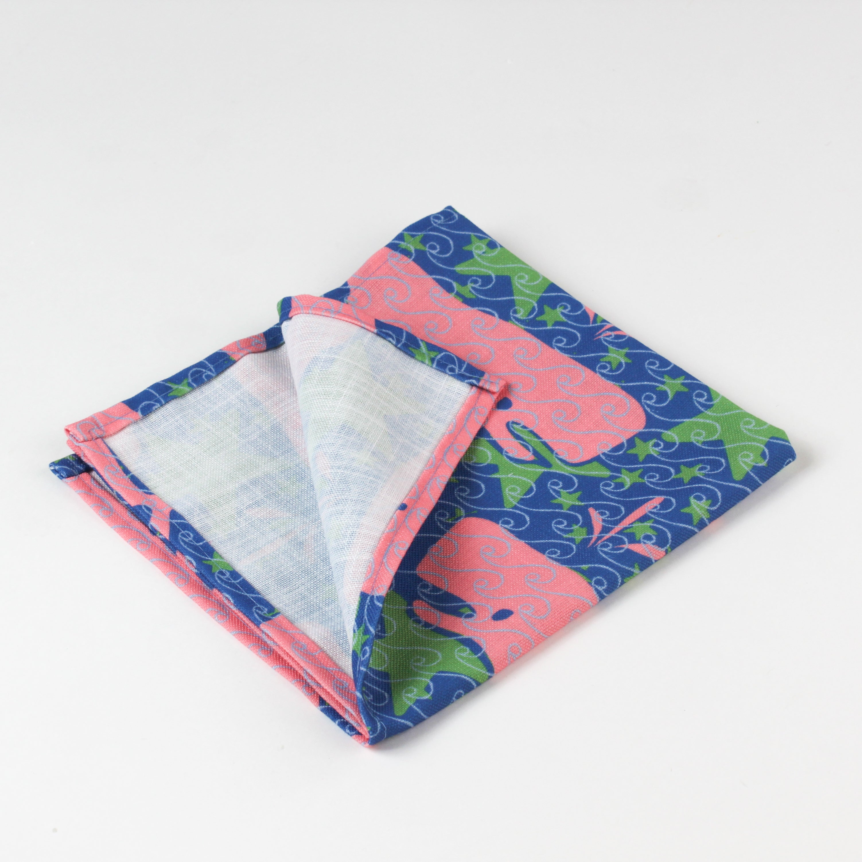 Close-up of folded cloth napkin showing pink whale and green seaweed print.