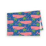 Folded Whale of a Time cotton tea towel featuring pink whales on a blue background with green ocean-inspired details.
