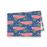 Folded Whale of a Time cotton tea towel featuring pink whales on a blue background with green ocean-inspired details.
