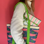 Whale of a Time canvas tote bag with lime straps and blue fabric with a repeating pink whale  and green star motif on models shoulder.