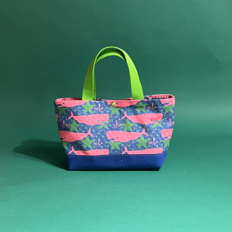 Small Whale of a Time canvas tote bag with lime straps and blue fabric with a repeating pink whale  and green star motif.