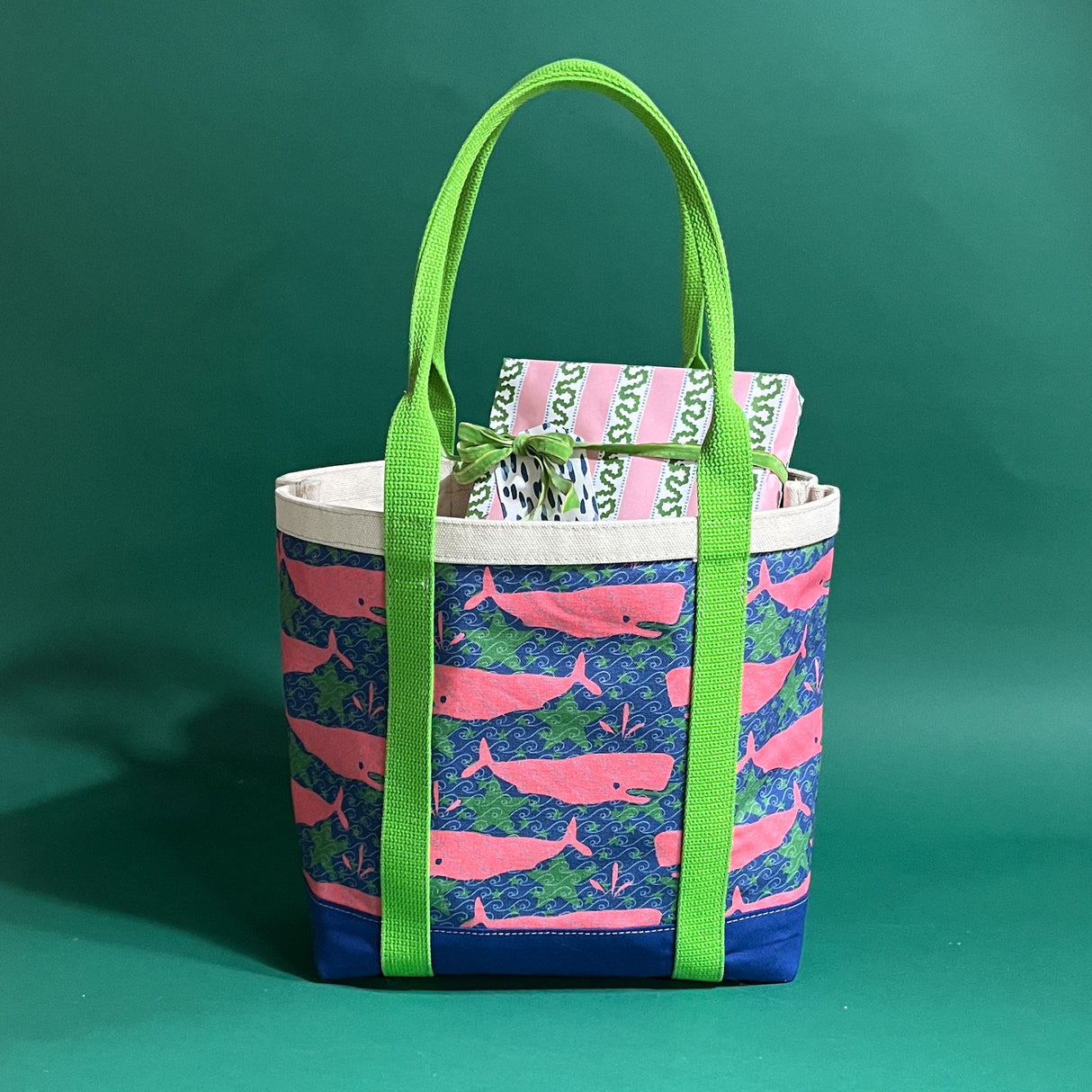 Large Whale of a Time canvas tote bag with lime straps and blue fabric with a repeating pink whale  and green star motif with presents sticking out of the top.
