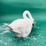 White ceramic swan on a green background with faux snow