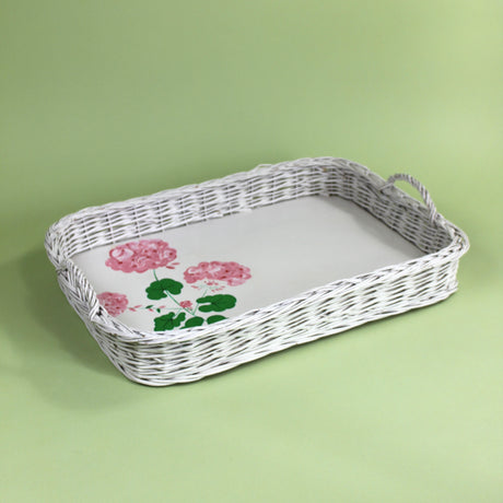 A white vintage wicker tray with a painted geranium motif on the tray base. 