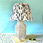 A vintage blue and white lamp featuring a white rattan base and a blue and white patterned lampshade.