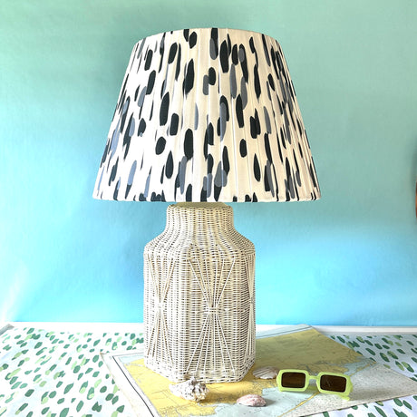 A vintage blue and white lamp featuring a white rattan base and a blue and white patterned lampshade. 