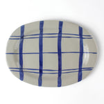 Oval ceramic blue and white platter painted with a blue check pattern on a white background