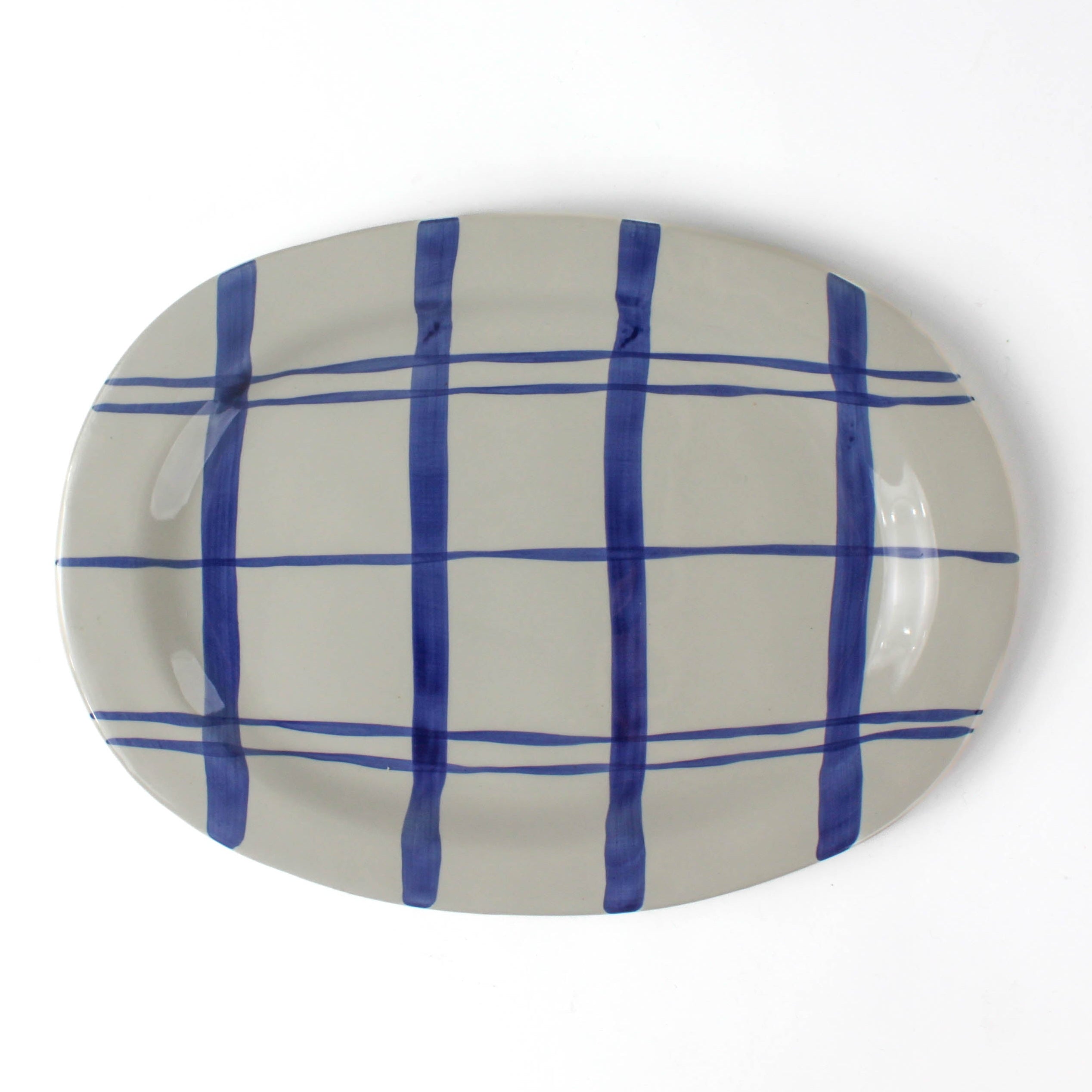 Oval ceramic blue and white platter painted with a blue check pattern on a white background