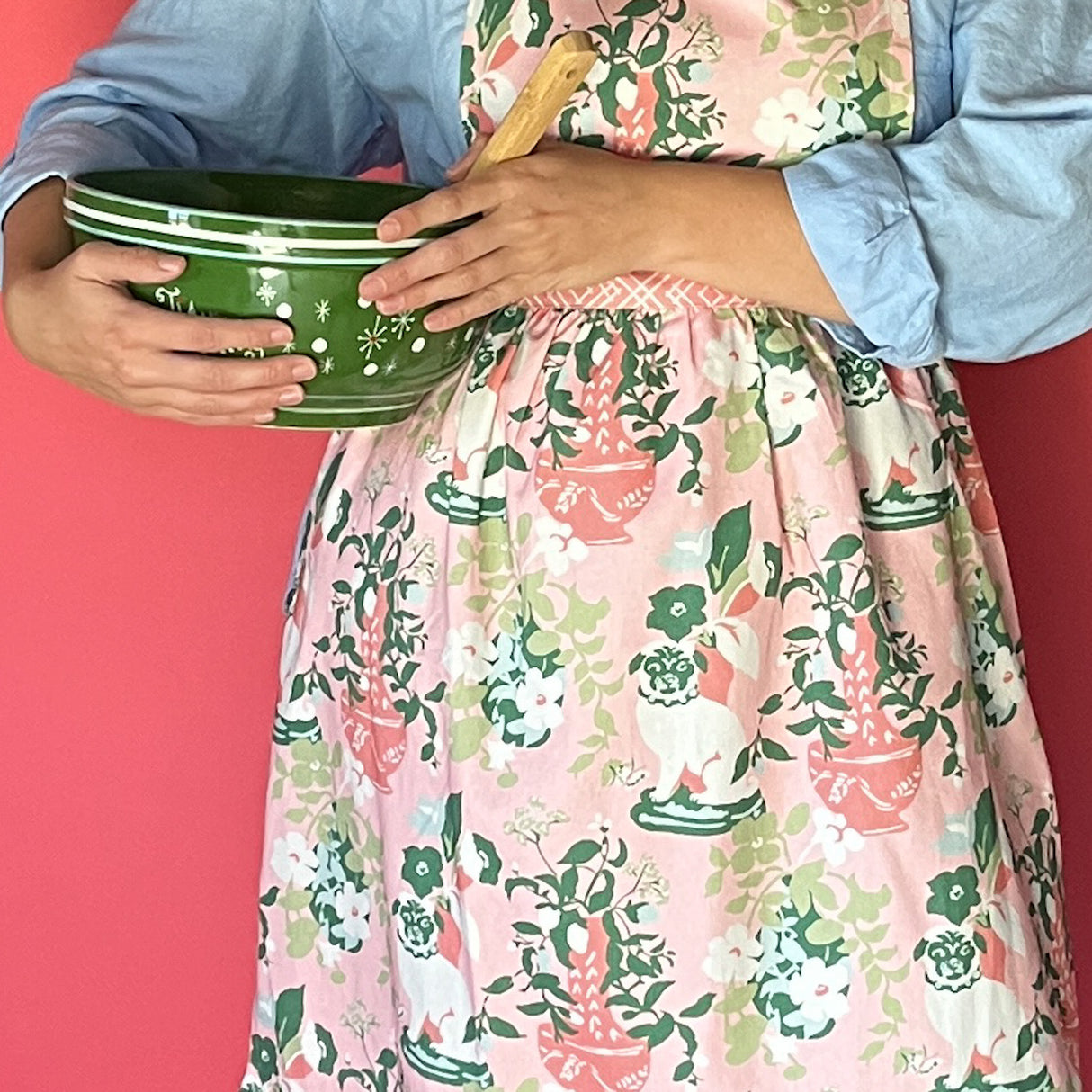 Person wearing Madcap Cottage Floral  holding a green bowl with a pink background