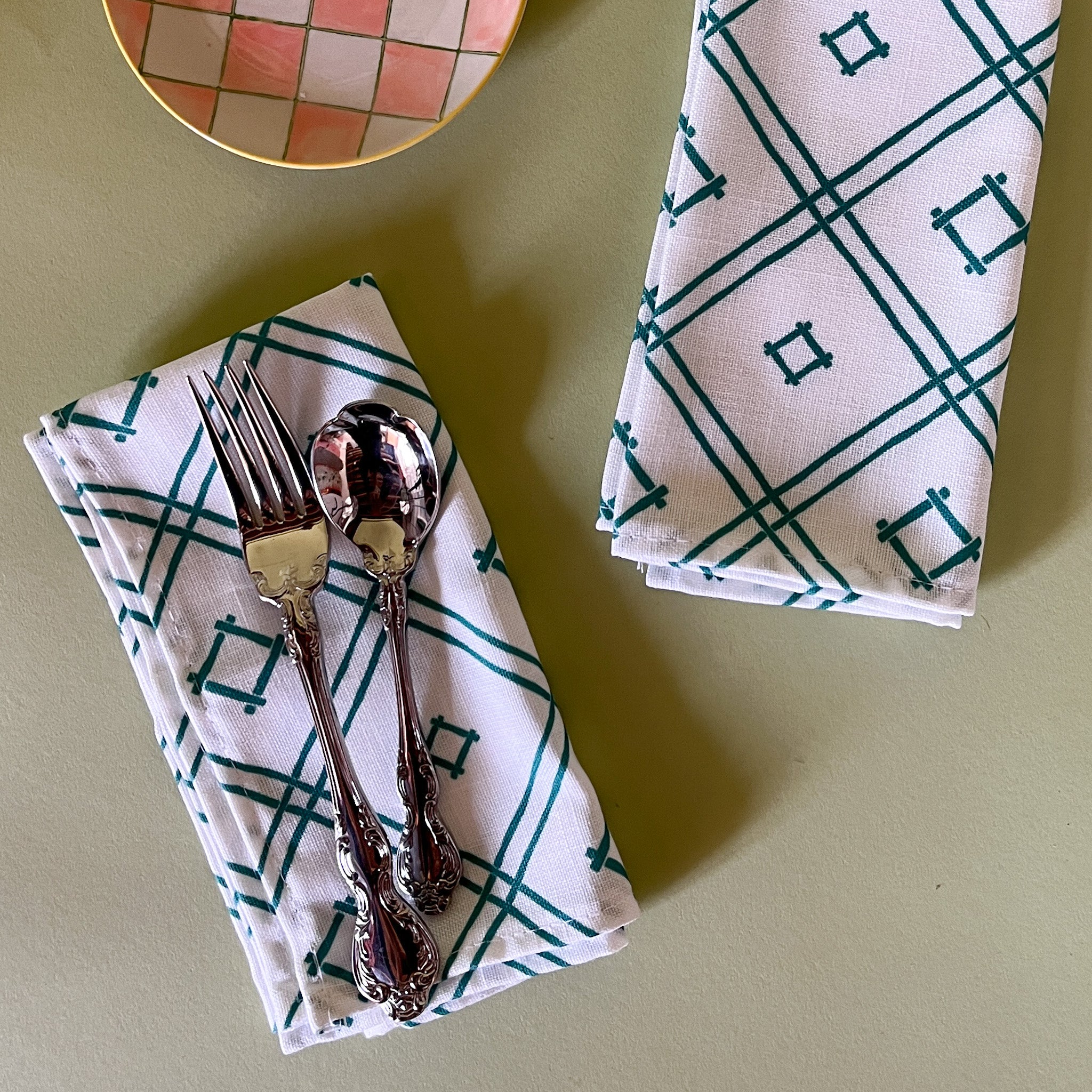 white and green cloth dinner napkins in Island House Small trellis print madcap cottage fabric against a light green background
