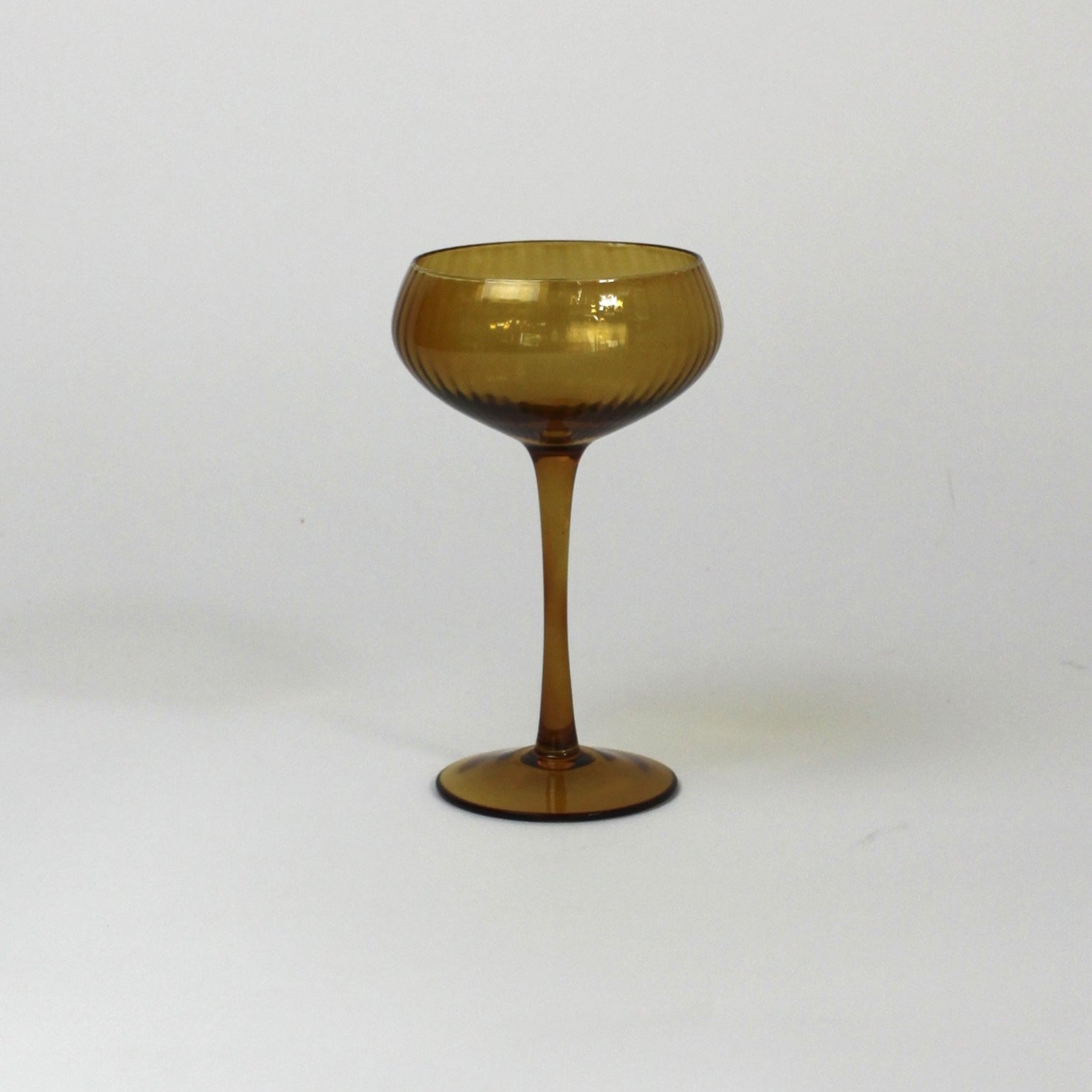 an amber colored coupe glass on a white background