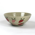 a large beige strawberry serving bowl decorated with pink and red strawberry motifs.