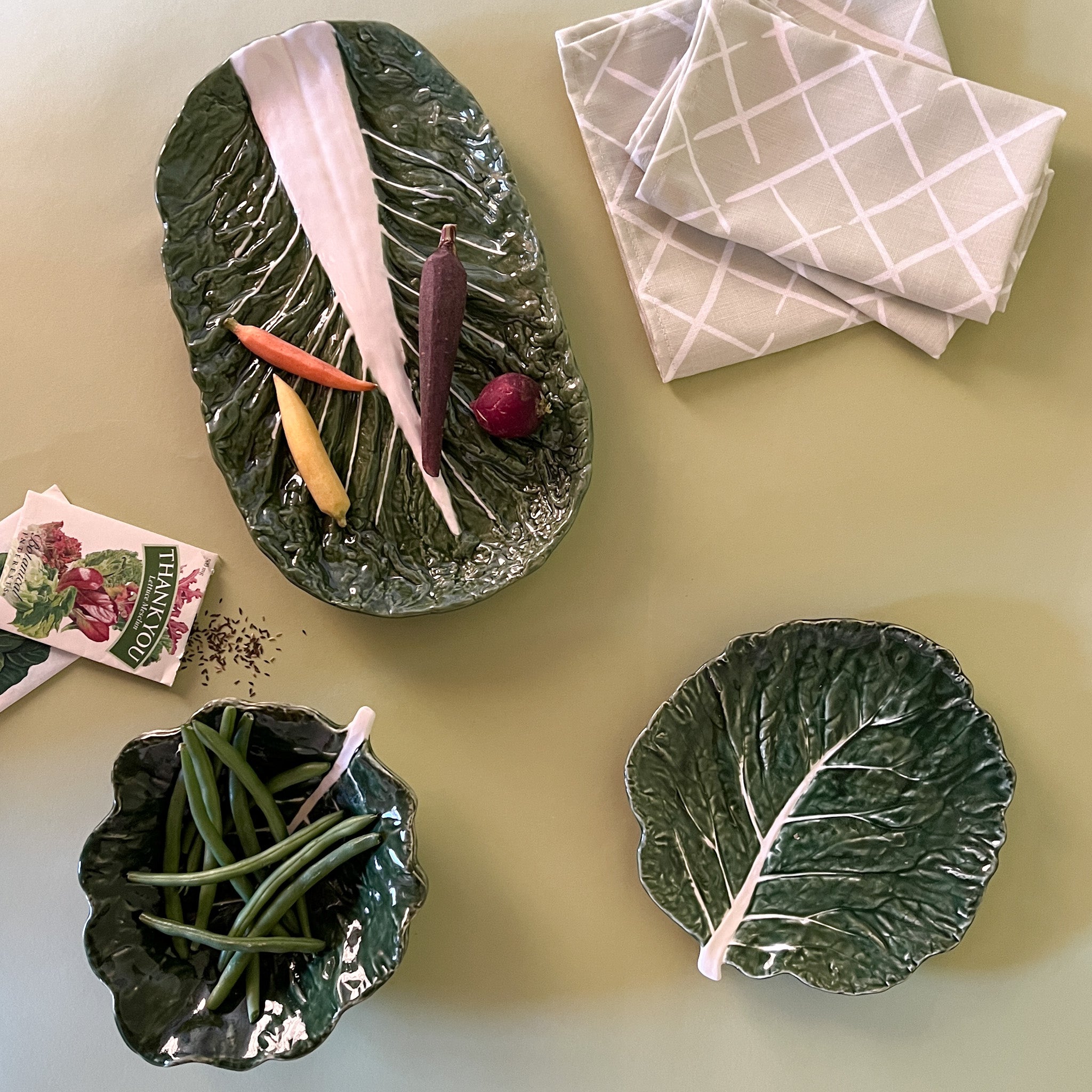 three cabbage leaf bowls filled with assorted vegetables resting on a light green background