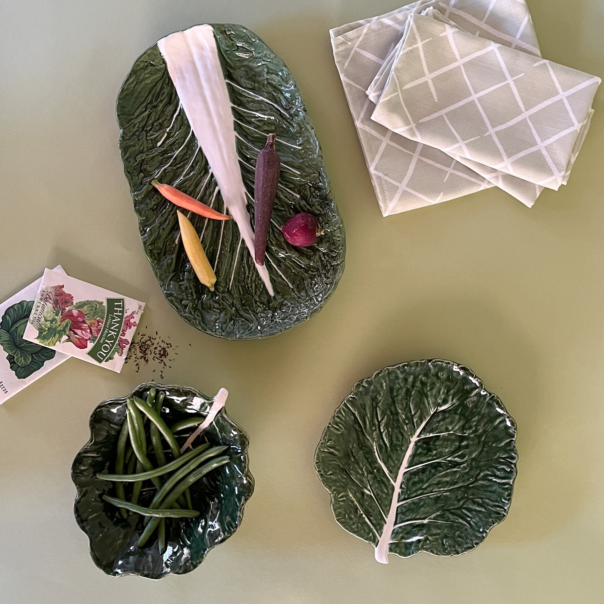 three ceramic cabbage plates surrounded by a seed packet and napkins from madcap cottage