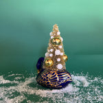 back of a Vintage Blue/Gold Ceramic Swan w/Gold Christmas Tree Centerpiece against a green background. 