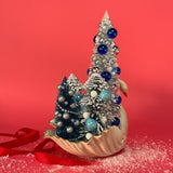 back of a a Vintage White/Gold Ceramic Swan w/ Silver/Blue Glitter Christmas Trees Centerpiece against a red background. 