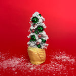 The back of a yellow coloured Vintage Distressed Ceramic Swan centerpiece with a Flocked Christmas Tree inside it against a red background. 