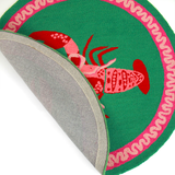 close up details of a round green and pink rug with a central red and pink lobster motif.
